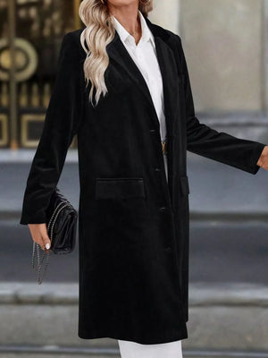 Black longline trench coat with lapel collar and buttoned front, worn by a woman holding a clutch.