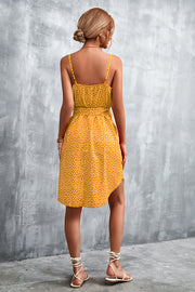 Mustard daisy print tie-waist slip dress with a ruffled hem and spaghetti straps.