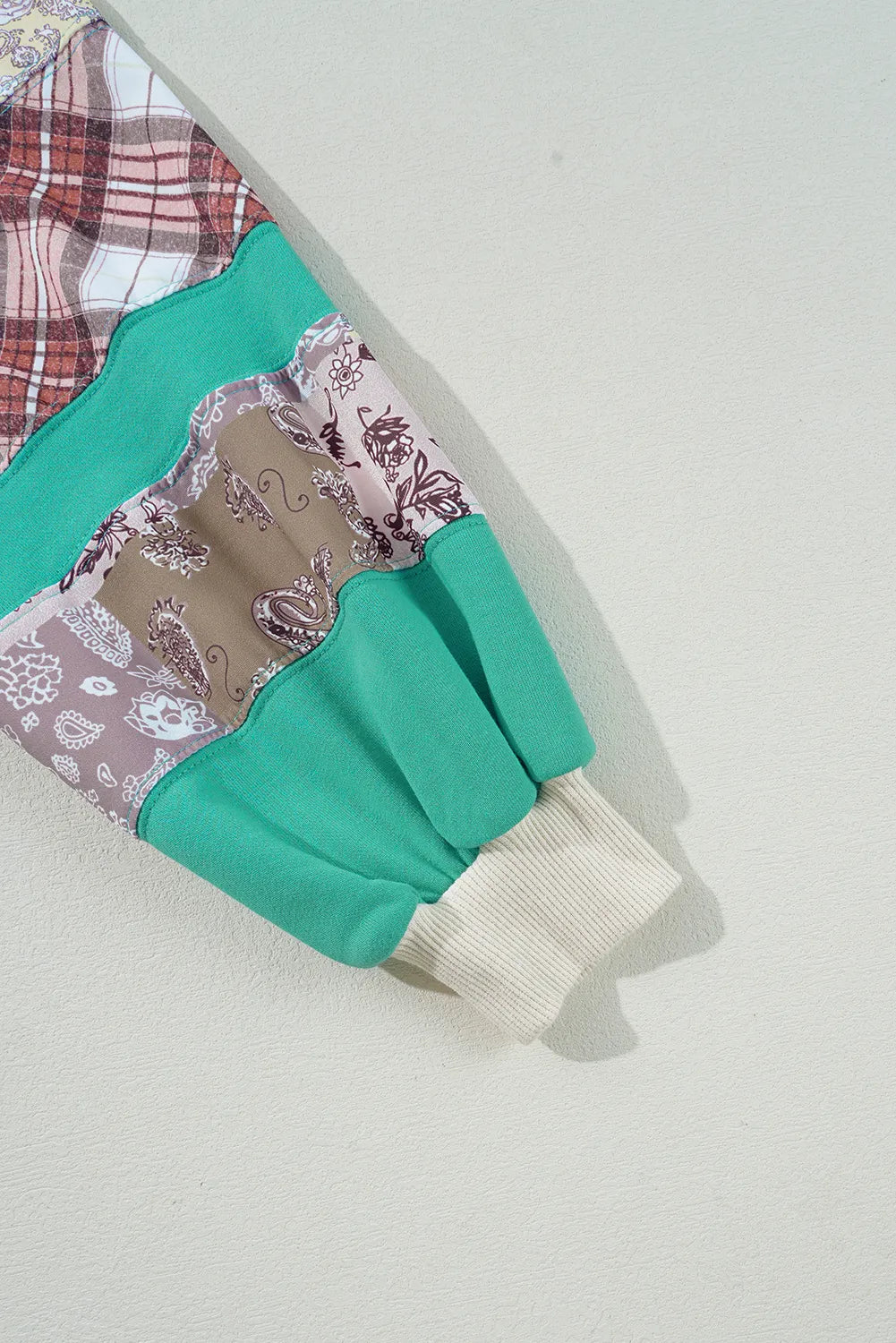 Patchwork raglan sleeve sweatshirt in turquoise with plaid and paisley patterns, ribbed cuff.