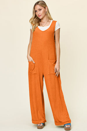 Tangerine ribbed knit tie-strap jumpsuit with wide legs and front pockets.