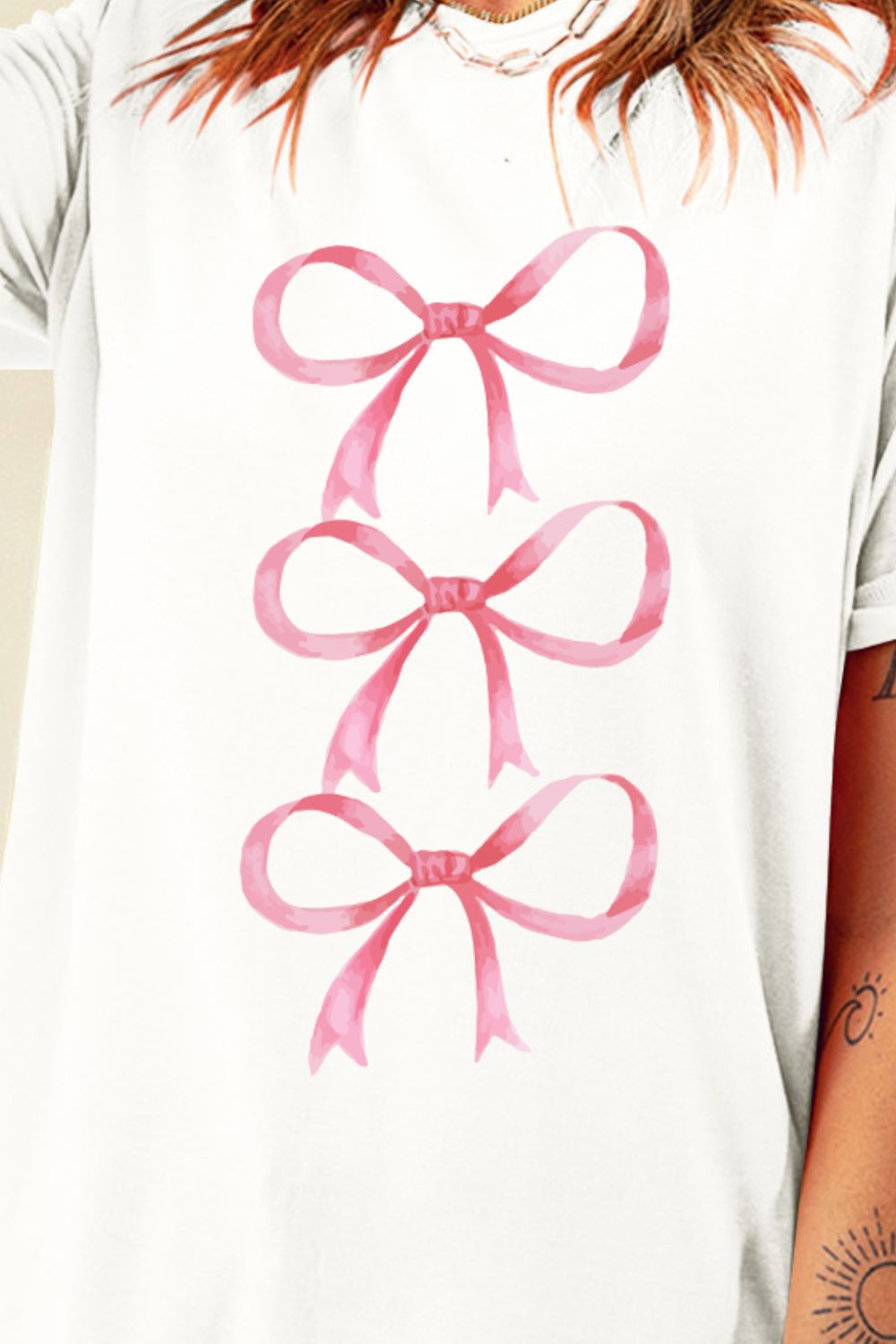 White t-shirt with three pink watercolor bows stacked vertically.