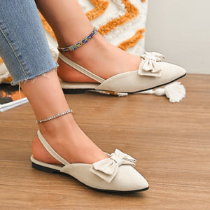 Beige slingback flats with bow detail and pointed toe.