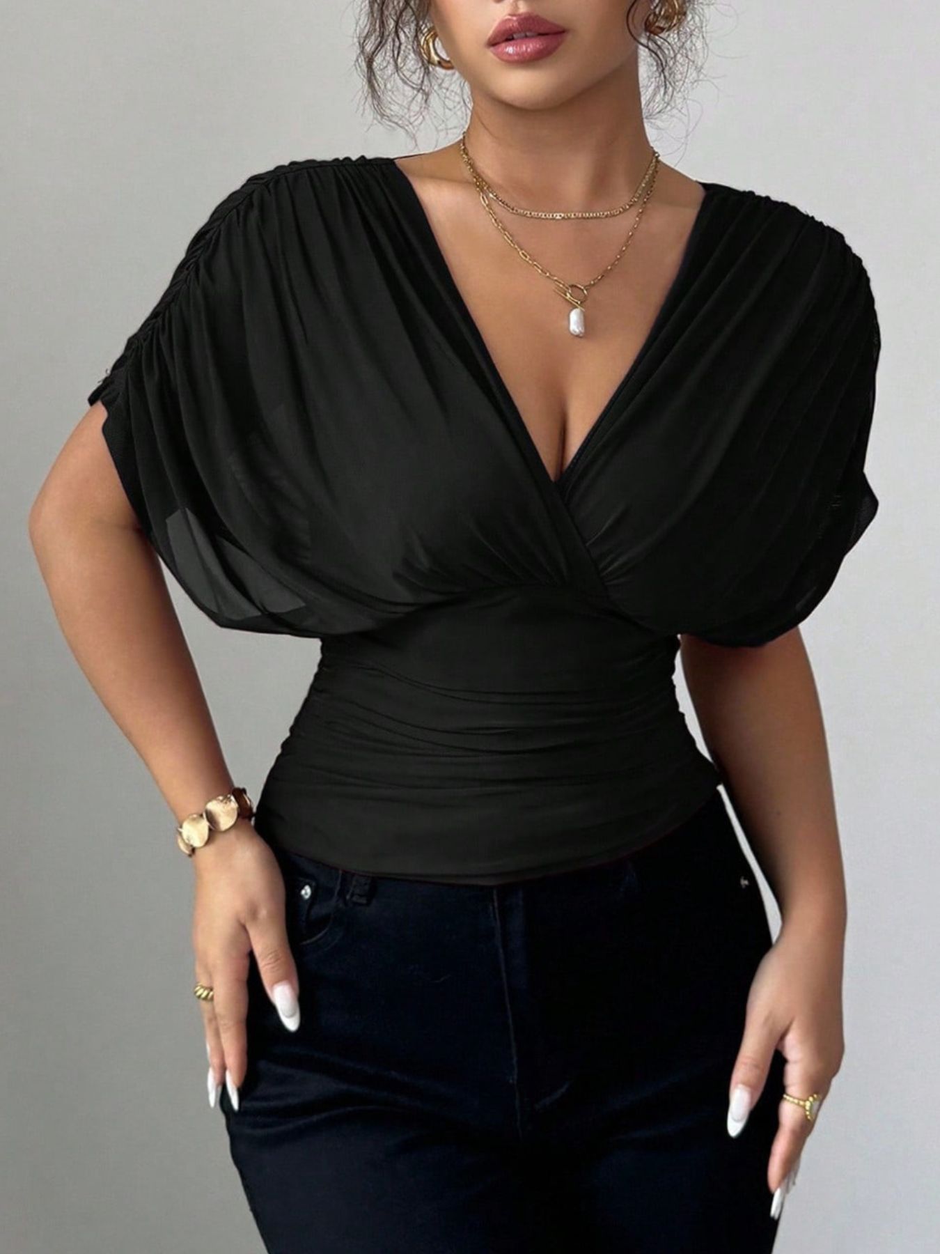 Black ruched surplice dolman sleeve top with V-neck and elastane fabric.