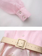 Pink midi dress with butterfly print, cinched waist belt, and button cuffs.