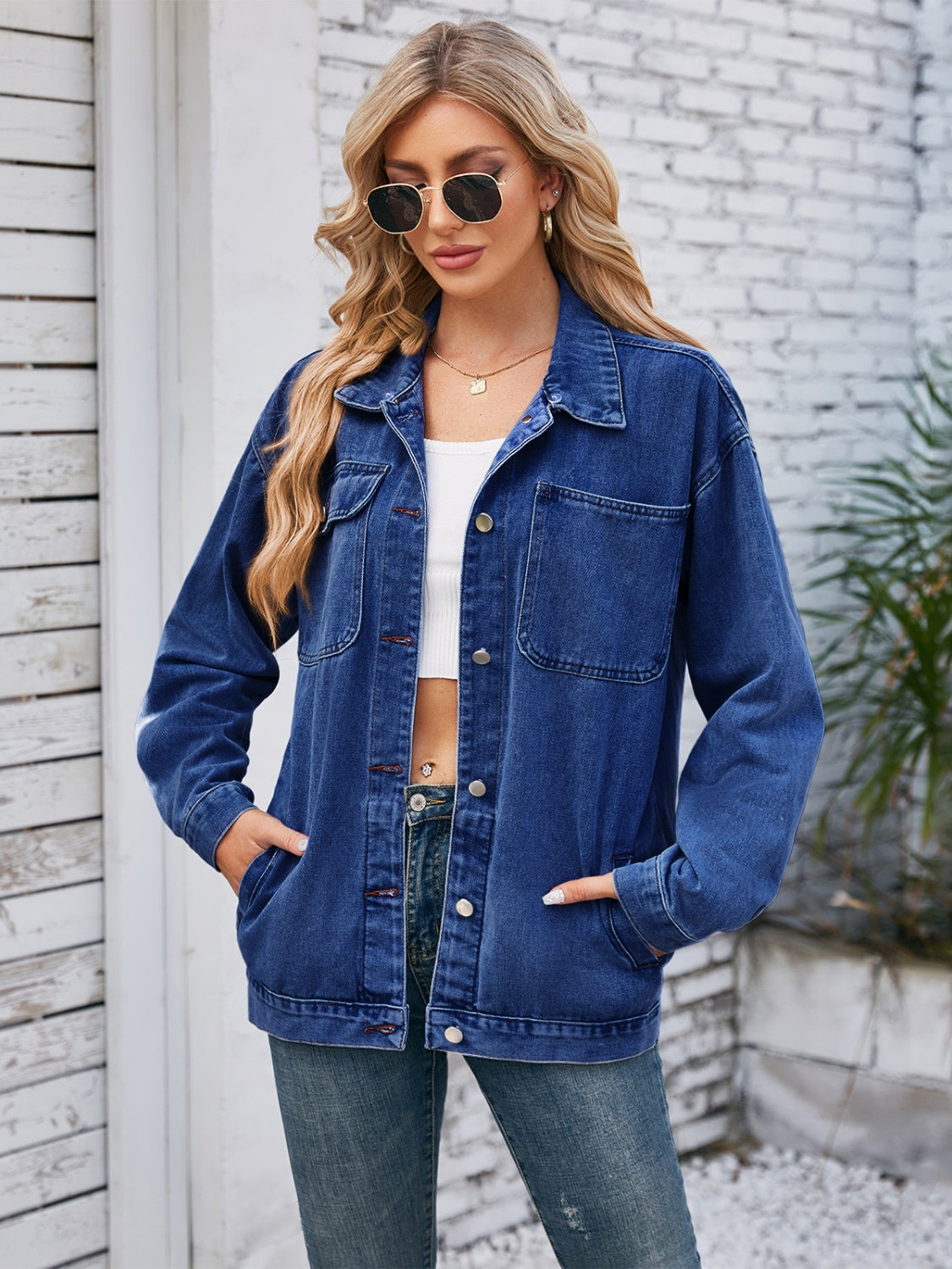 Dark blue oversized denim jacket with hood detail, buttoned front, and chest pockets.