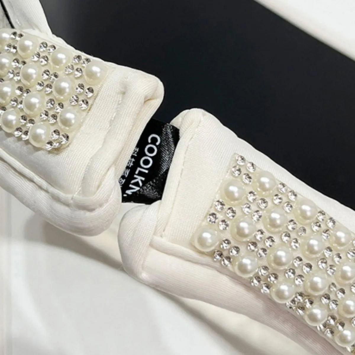 White tweed visor with pearl and rhinestone embellishments on the band.