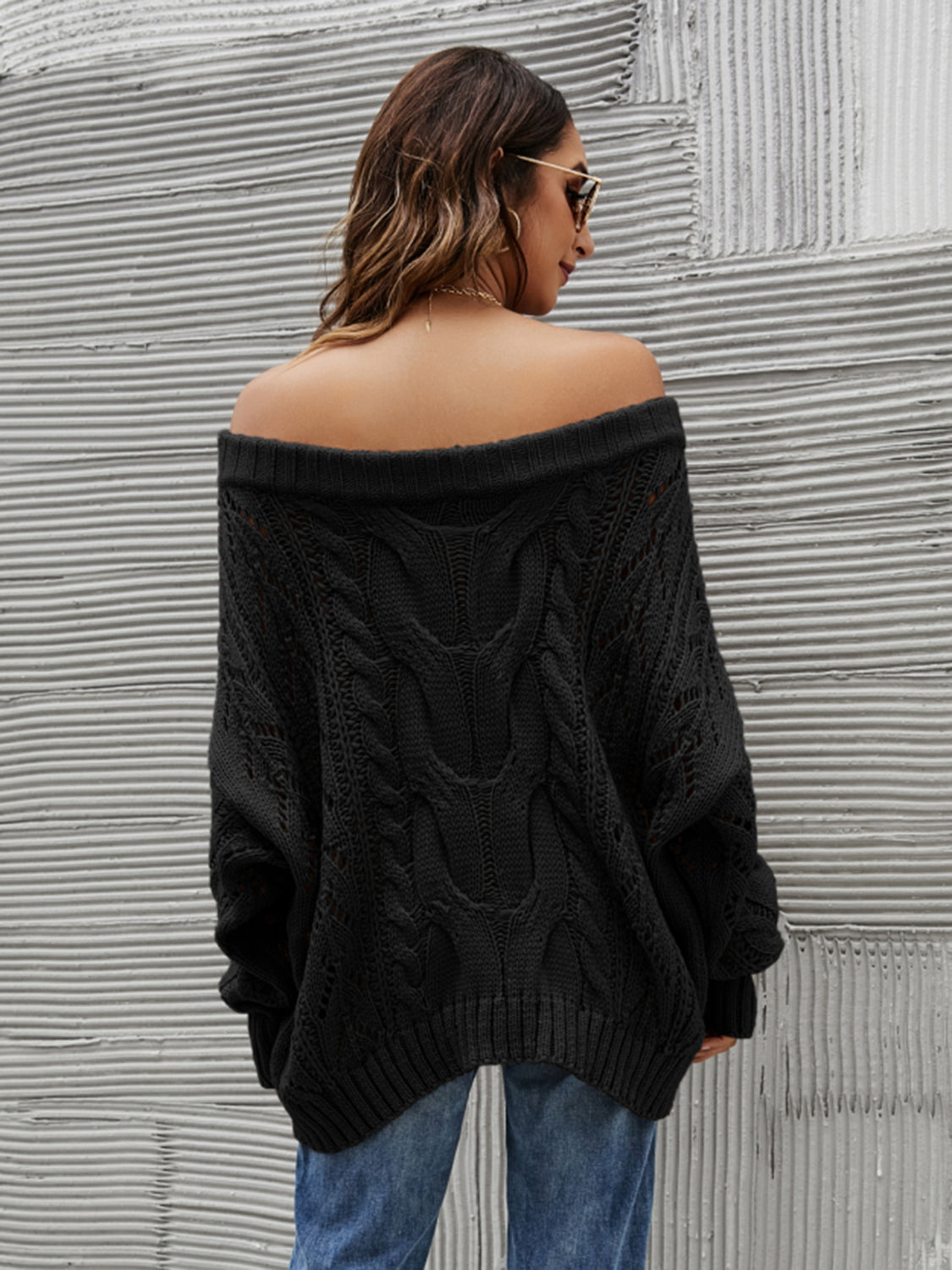 Black cable knit off-shoulder slouch sweater with detailed knit pattern.