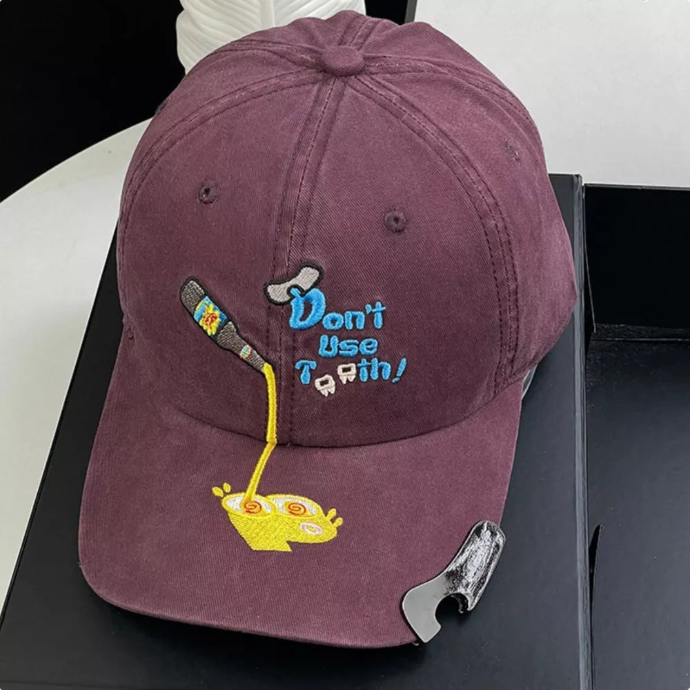 Deep purple baseball cap with embroidered cartoon and text detail.