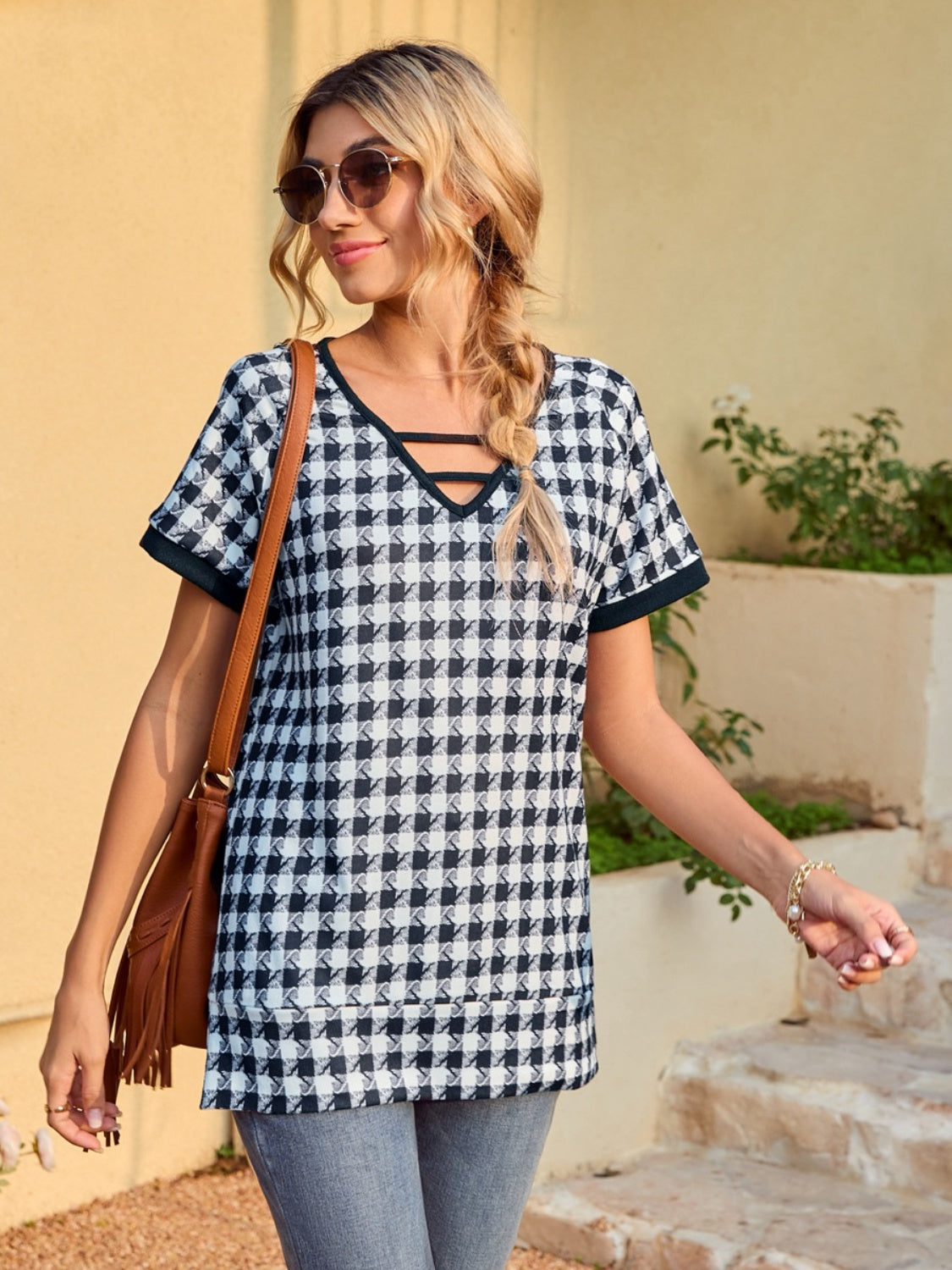 Houndstooth tunic top with cutout neckline and short sleeves, styled casually with jeans.