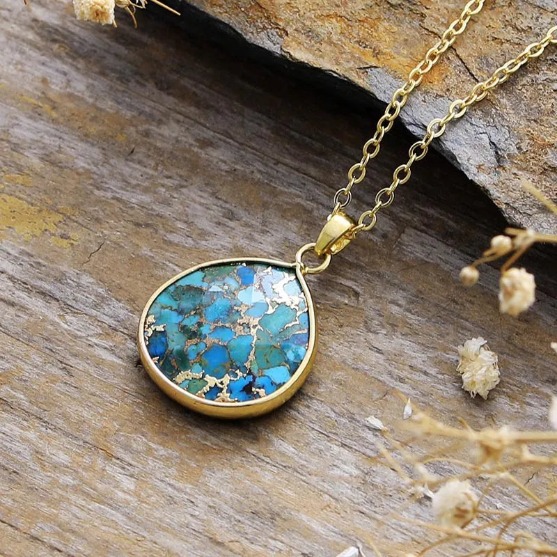 Gold chain necklace with a teardrop turquoise stone pendant framed in gold.
