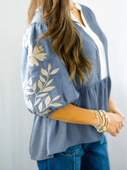 Blue peplum blouse with elbow sleeves and embroidered floral detail