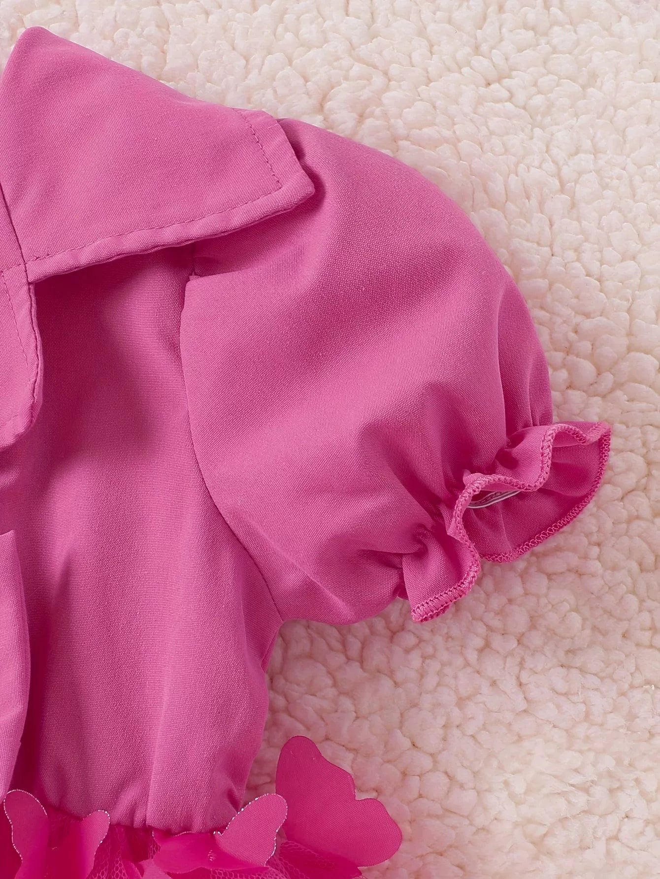 Pink baby dress with collared neckline, ruffled short sleeves and butterfly applique detail.