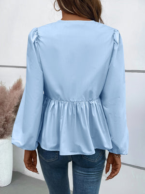 Light blue peplum blouse with gathered sleeves and hem, paired with jeans.