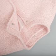 Blush pink textured bouclé bomber jacket with rounded neck and snap closure detail.