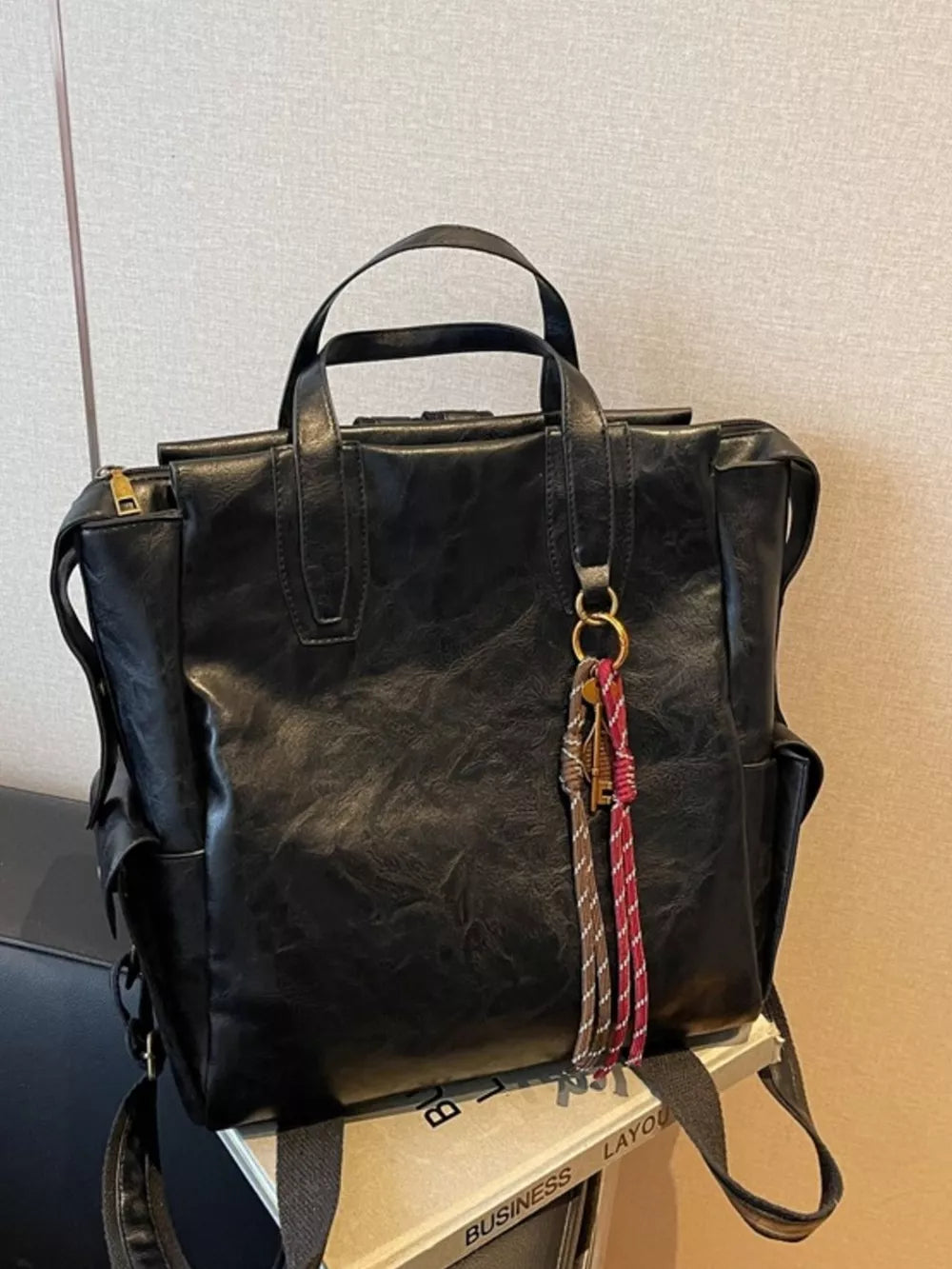 Black leather convertible backpack with tassel and key charm detail
