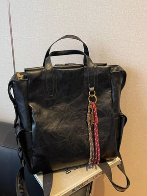 Black leather convertible backpack with tassel and key charm detail