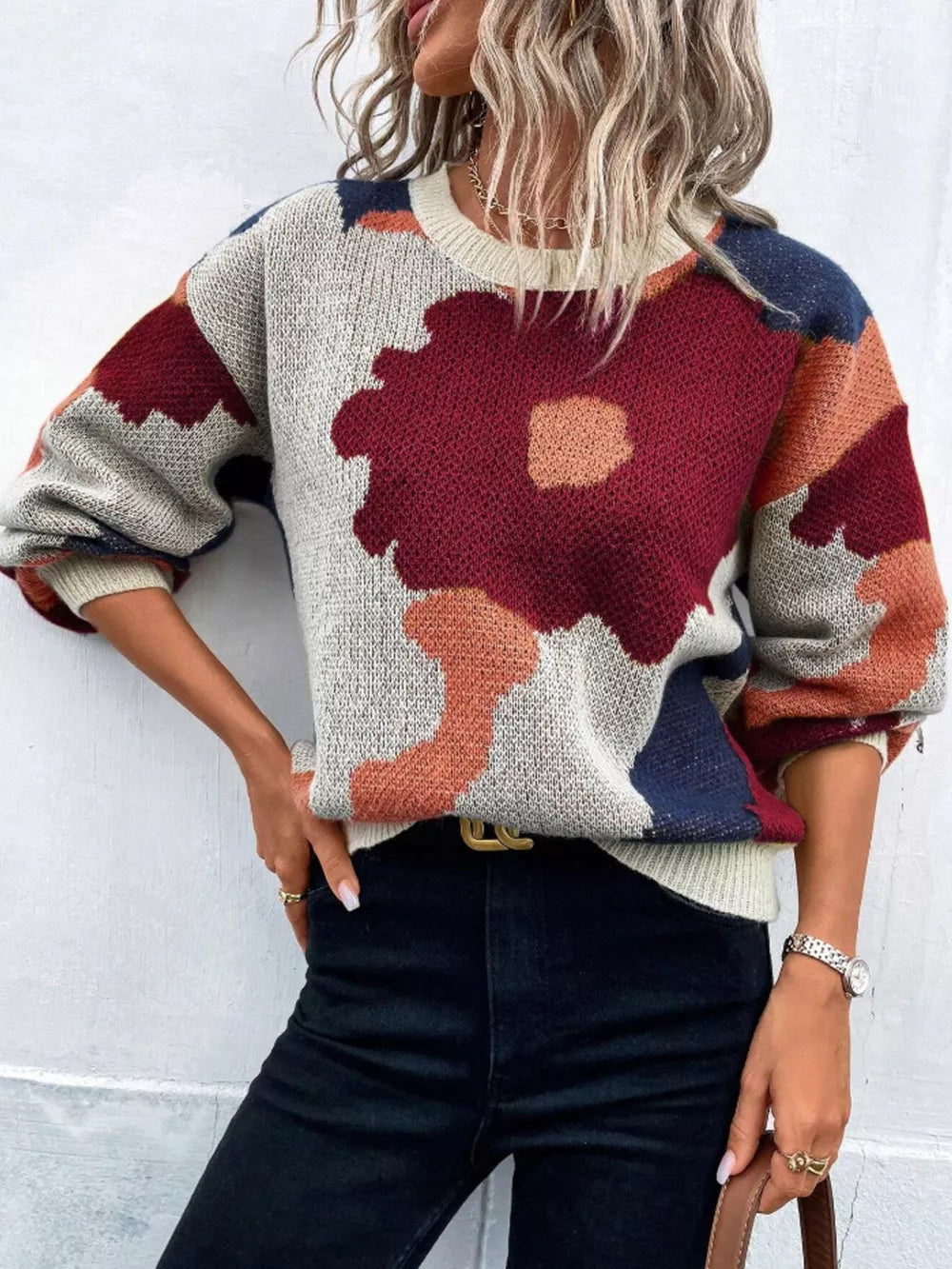 Abstract floral knit sweater with round neck in burgundy, orange, blue, and cream.