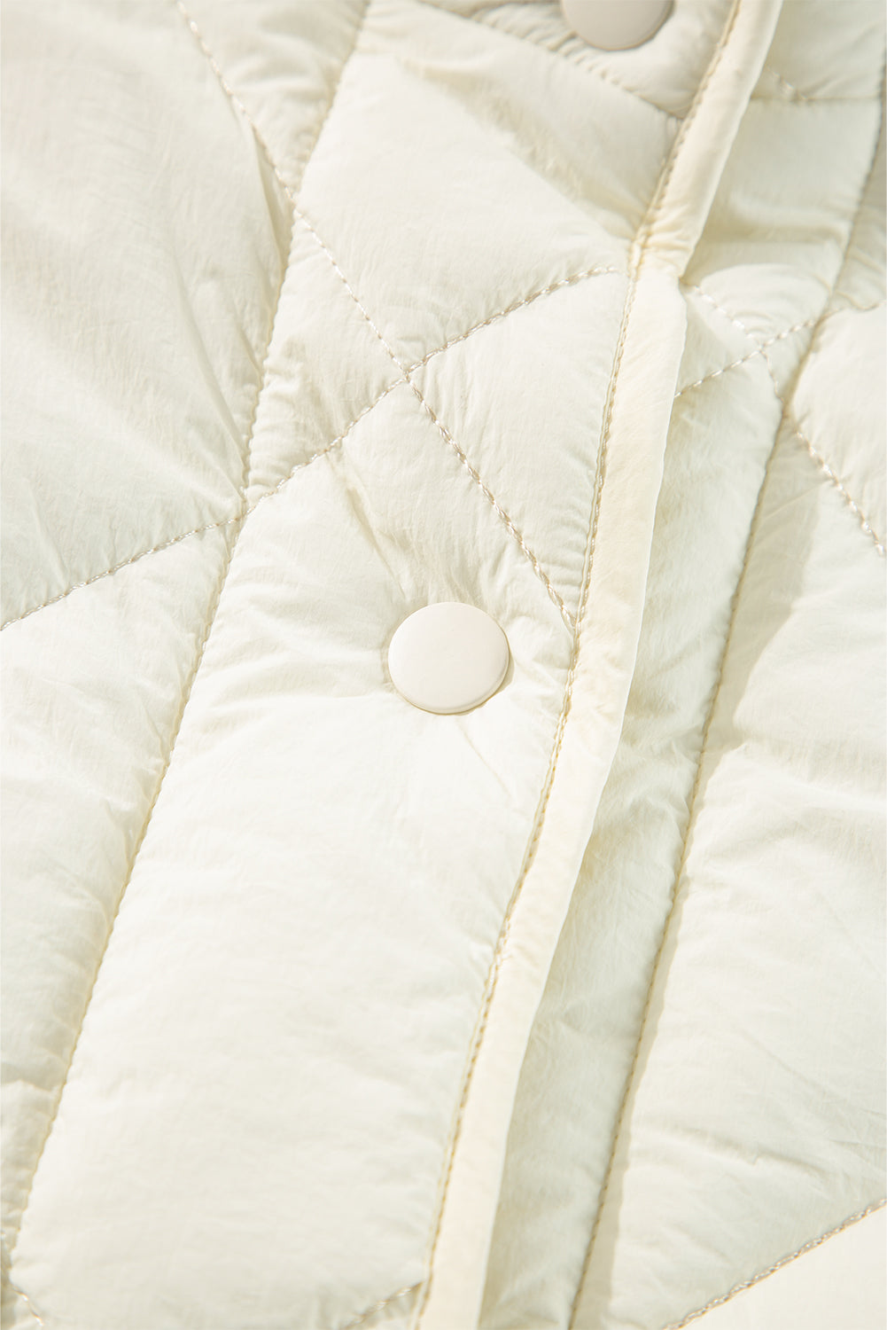 Ivory quilted vest with diamond stitching and a snap closure detail.