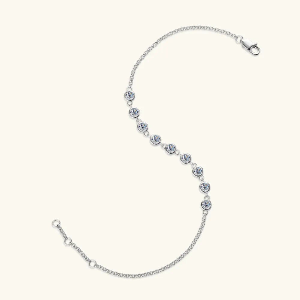 Silver moissanite tennis bracelet with bezel-set stones and a delicate chain.