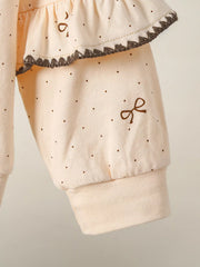 Tan polka dot baby outfit with ruffle trim and embroidered bow detail.