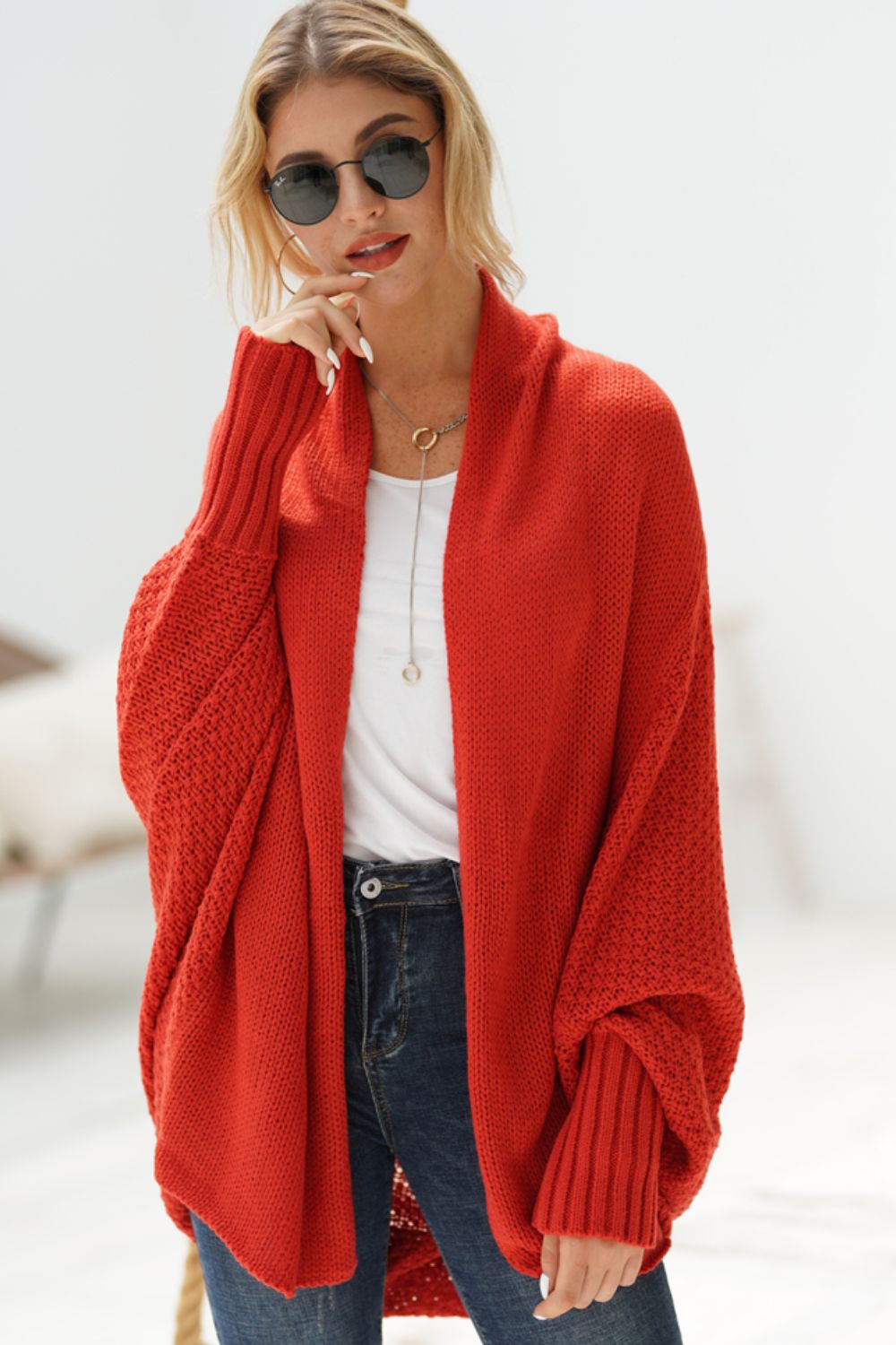 Red batwing knit cardigan with drape front and textured sleeves.
