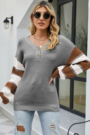 Waffle knit henley sweater in grey with striped sleeves and button neck detail.