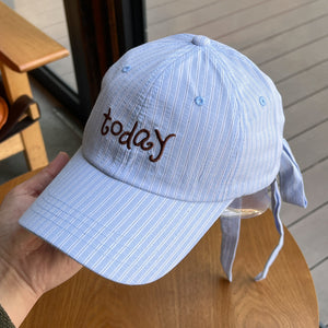 Pastel blue striped cotton baseball cap with embroidered "today" and tie back detail.