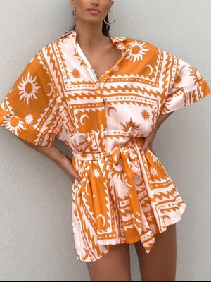 Celestial print wrap romper in orange and pink with short sleeves and a tie waist.