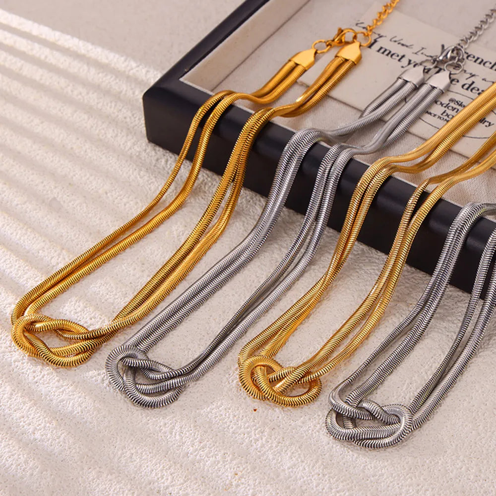 Knot detail serpent necklace in gold and silver, featuring a unique knotted design.