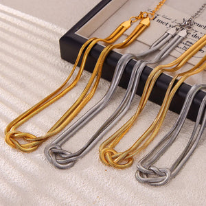 Knot detail serpent necklace in gold and silver, featuring a unique knotted design.