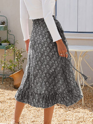 Asymmetric wrap skirt in gray with a leaf print, featuring a tie waist and ruffled hem.