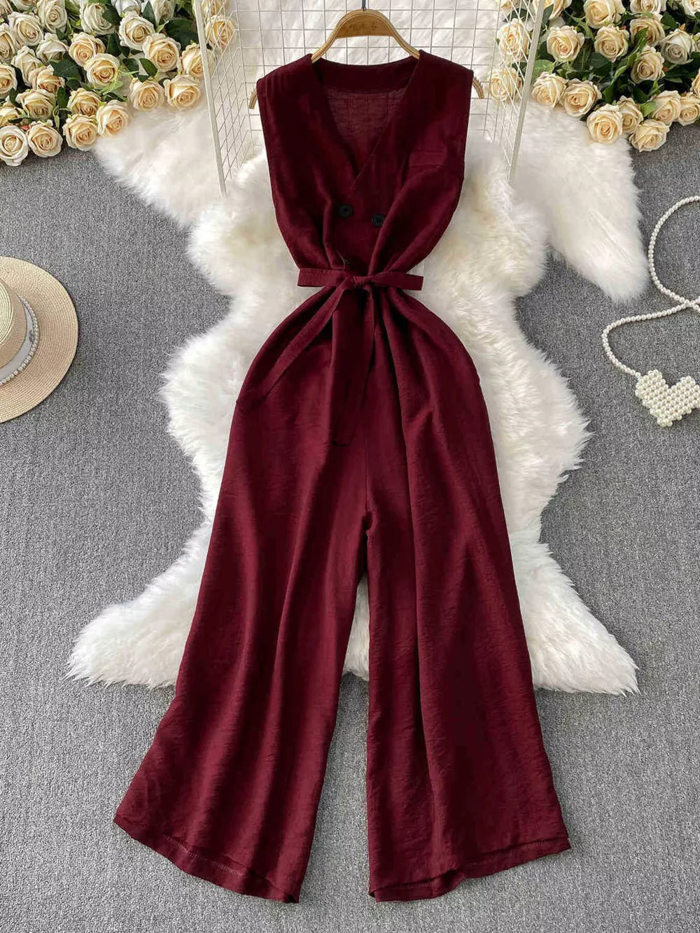 Burgundy V-neck wide leg jumpsuit with tie belt and double button detail.