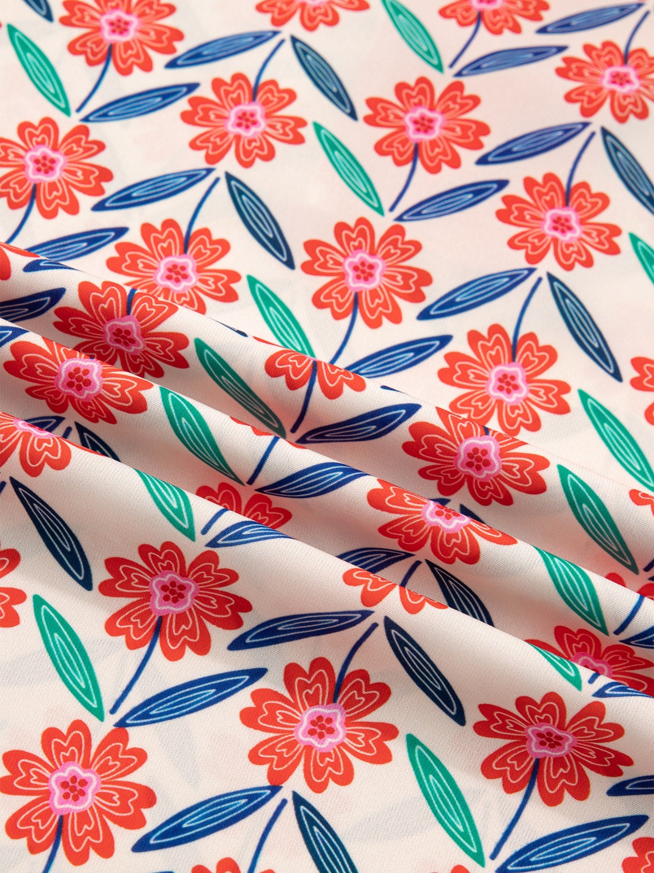 Floral ruffled V-neck shirt with striped trim in a cream fabric with red flowers and blue/green leaves.