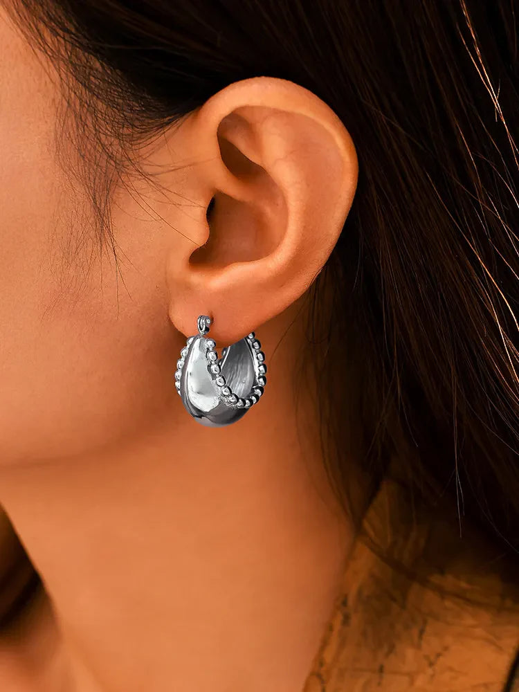 Sculpted silver-tone crescent earrings with beaded edges.