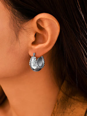 Sculpted silver-tone crescent earrings with beaded edges.