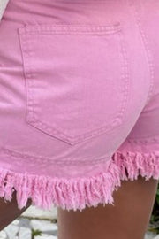 Pink denim shorts with high rise and frayed hem detail.