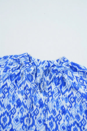 Royal blue ikat print V-neck blouse with tie detail and gathered neckline.