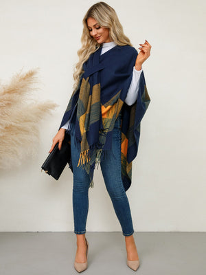 Navy plaid fringe cape with asymmetric cut and tie detail, worn by a woman with jeans and heels.