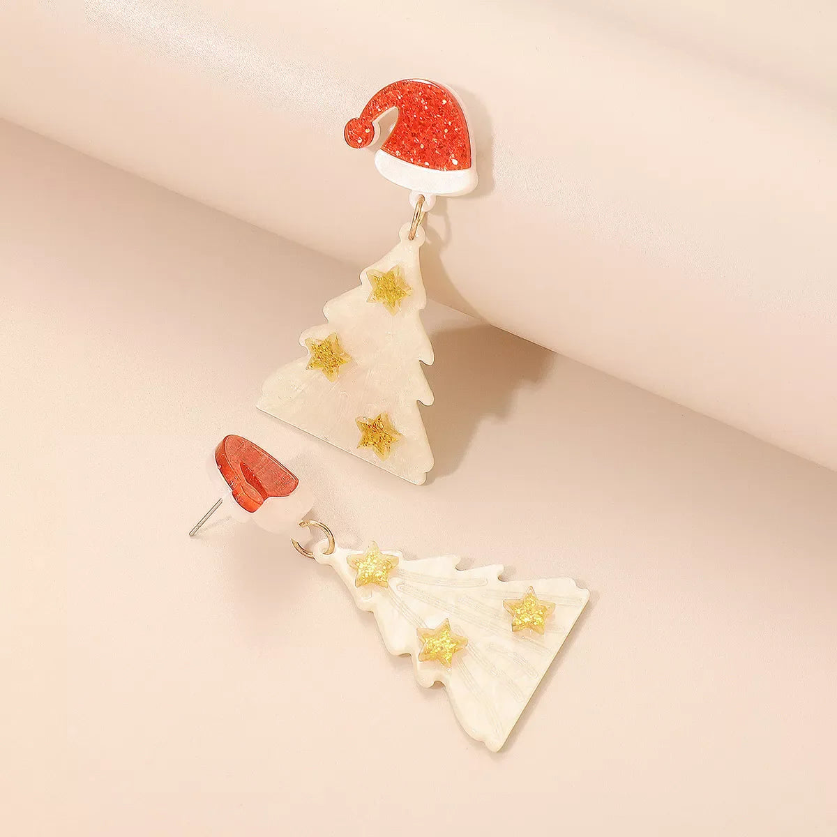 White acrylic Christmas tree dangle earrings with gold stars and Santa hats.