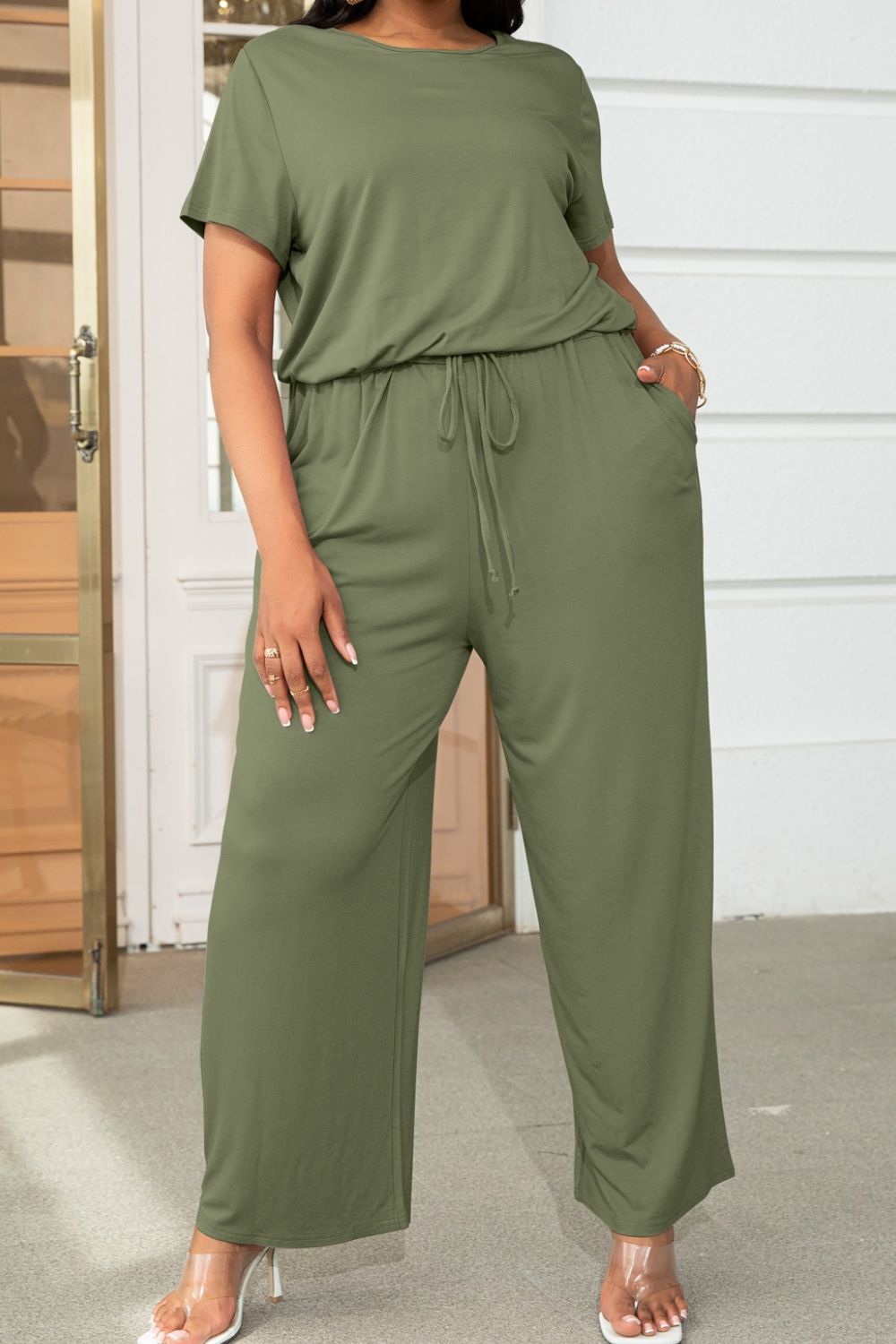 Moss green relaxed fit jumpsuit with short sleeves, drawstring waist, and wide legs.