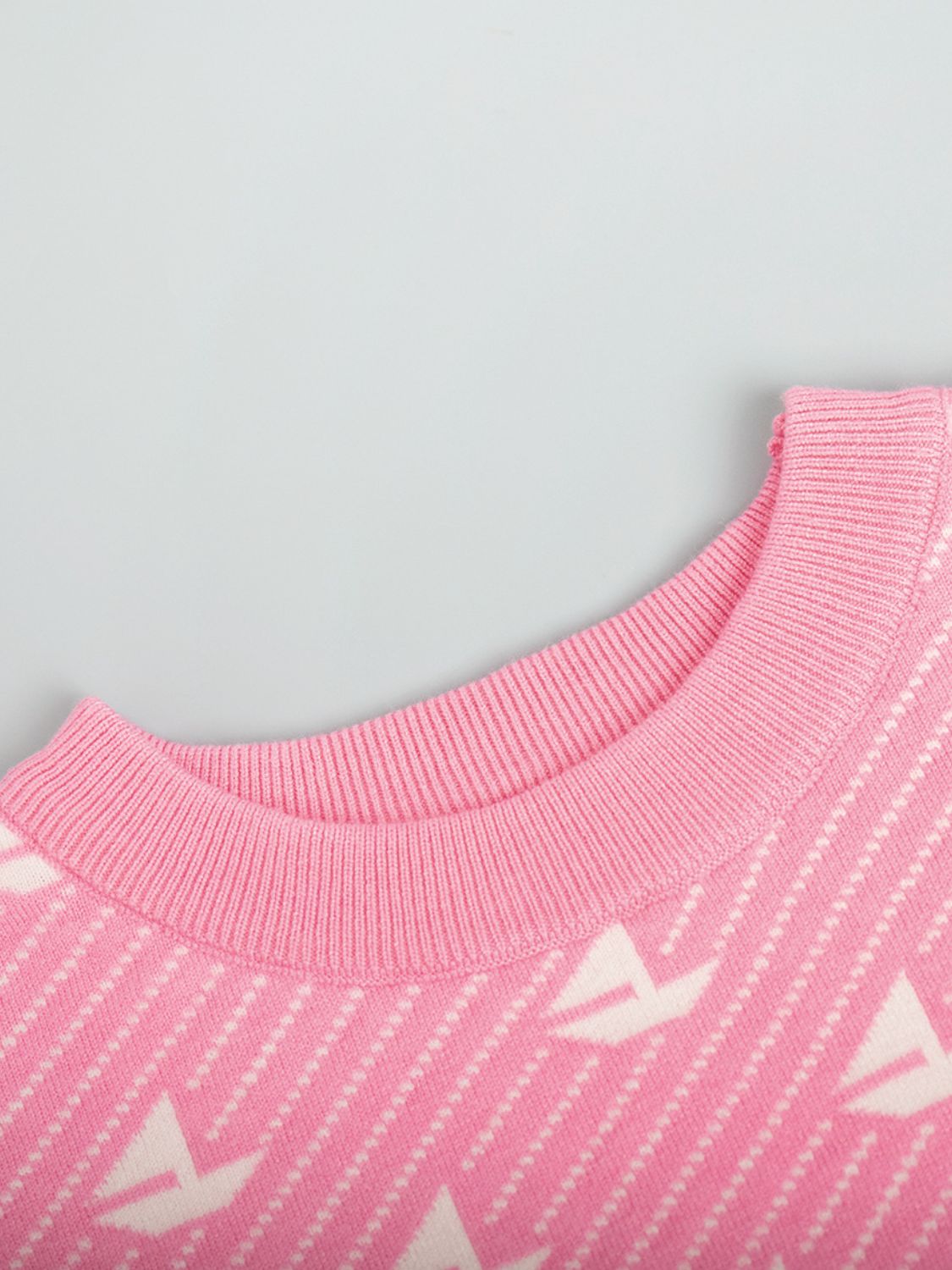 Blush pink knit sweater with sailboat jacquard pattern and ribbed crewneck.