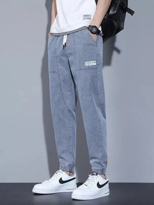 Light wash denim joggers for men with drawstring and patch detail.