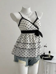 White polka dot camisole with black lace trim, tiered ruffles, and a black bow detail.