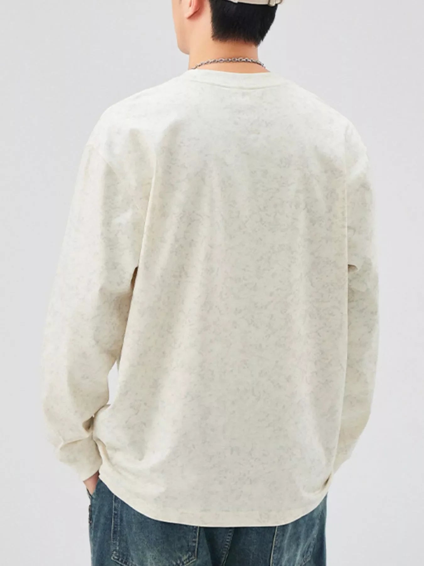 Oversized long-sleeve tee in light apricot with a subtle all-over pattern.
