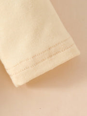 Baby bodysuit sleeve detail with double stitching in cream cotton