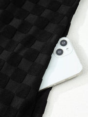 Chic checkered wide-leg jumpsuit in black with a hidden pocket detail.