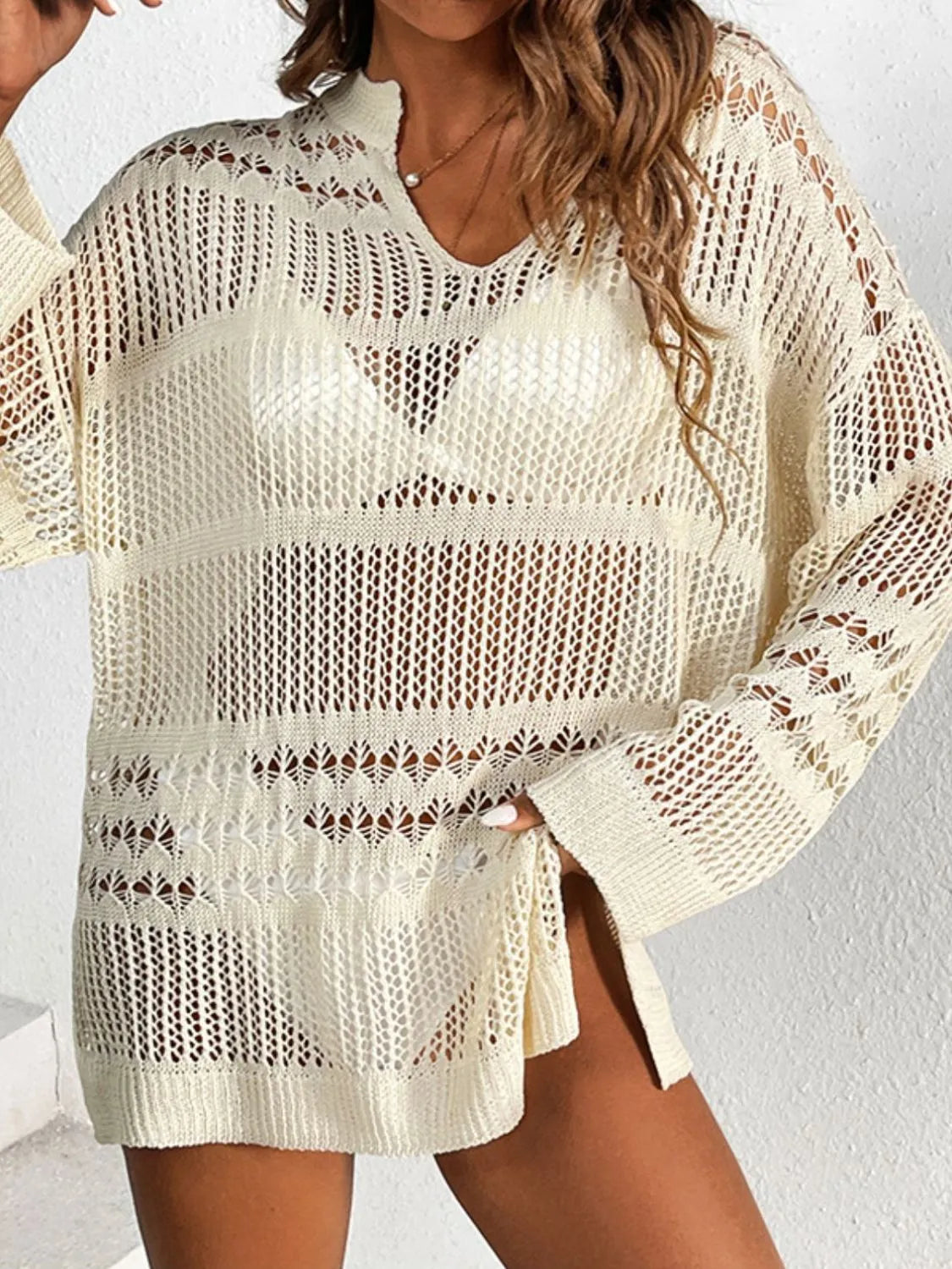 Open-knit beige beach cover-up with V-neck, long sleeves, and slit hem.