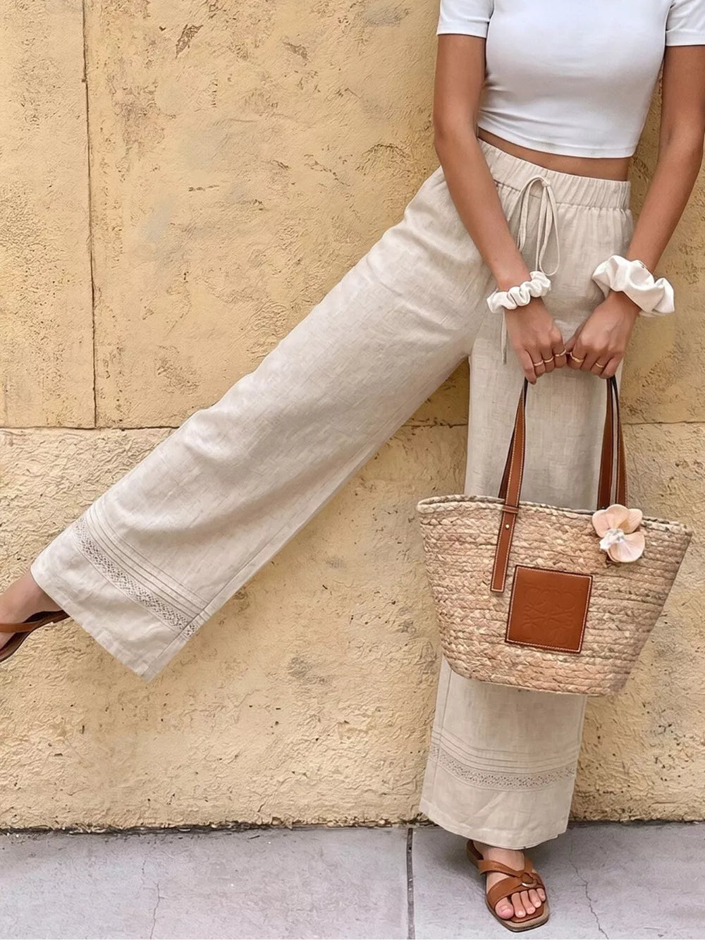 Beige maternity wide-leg trousers with drawstring and lace trim detail.