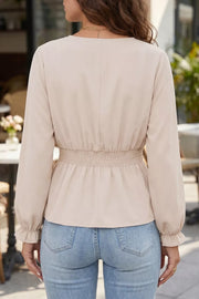 Elegant V-neck blouse in beige polyester with smocked waist and ruffled cuffs.