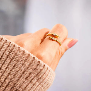 Gold bypass ring with spiked ends and cubic zirconia accents on a finger.